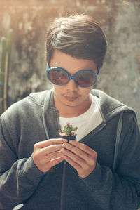 Asia man with glasses holding a cactus in hand , man posing with cactus.