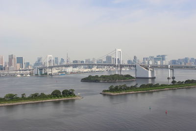 Bridge over river in city against sky