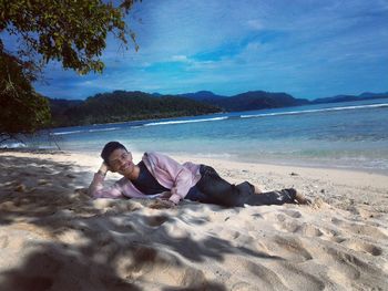 Men lying on beach against sky