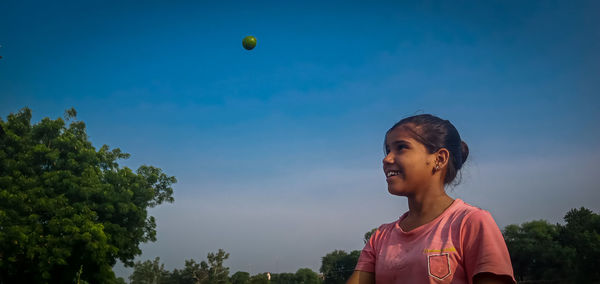 Boy playing with ball against sky