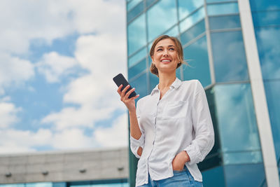 Close-up of smiling businesswoman standing by glass outdoors