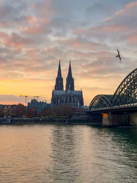 River in city against sky during sunset