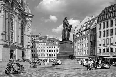 Statues on street amidst buildings in city against sky