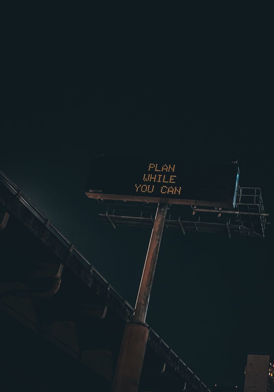 LOW ANGLE VIEW OF INFORMATION SIGN AGAINST BUILDING AT NIGHT