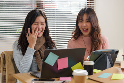 Portrait of young woman using laptop at office