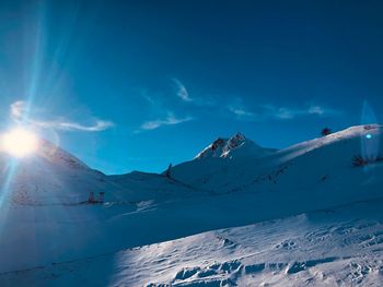 Scenic view of snow covered mountains against blue sky