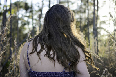 Rear view of young woman standing against trees