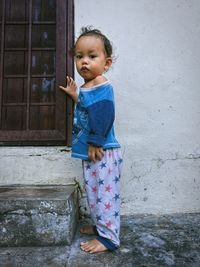 Full length portrait of cute baby boy standing by house