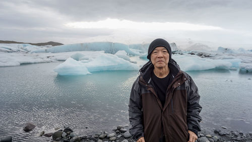 Mature man standing against glacier