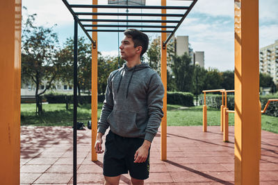 Young man bodybuilder having break during his workout in a modern calisthenics street workout park