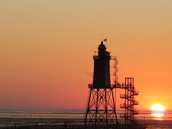 Silhouette lighthouse against sky during sunset