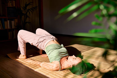 Woman practicing yoga and meditation at home sitting on yoga mat. 