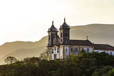 Old church in ouro preto city on top of hill and surrounded by hills during sunset