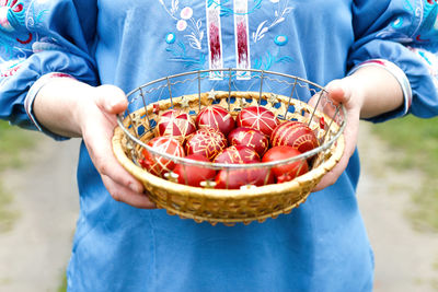 Easter eggs. female hands holding basket of colored red eggs on nature background. holiday concept