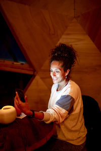 Woman using a mobile phone while relaxing in a dome tent.