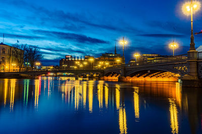 Illuminated bridge over river against sky at night