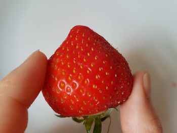 Close-up of hand holding apple against white background