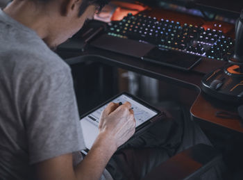 A young caucasian guy sits in a work chair and browses an online map on a tablet for ordering food