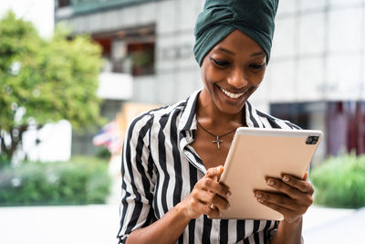 Portrait of smiling young woman holding smart phone