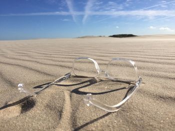 Surface level view of clear glasses on a sandy beach