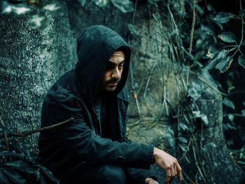 Man looking away while sitting in forest