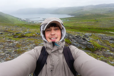 Tourist man making selfie on hill near skarsvag. landmark on lofoten islands. norway.