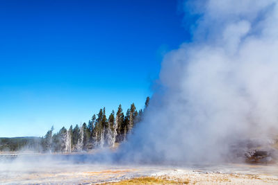 Steam emitting from landscape against sky