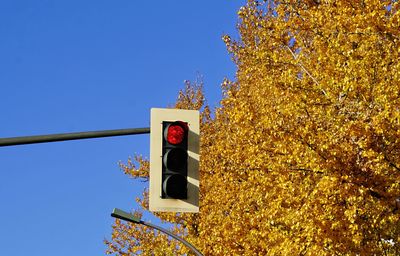 Low angle view of road sign against clear blue sky