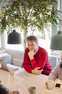 Side view of boy using digital tablet while sitting in office