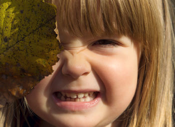 Close-up portrait of cute girl holding leaf