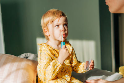 A little daughter paints her lips while playing at home with her mother.