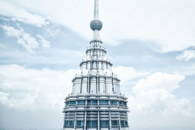 High section of petronas towers against cloudy sky