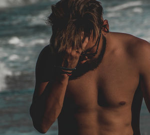 Midsection of shirtless man standing at beach