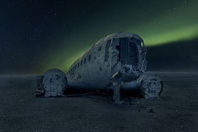 Abandoned airplane on land against sky at night