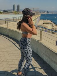 Woman standing by railing against sea