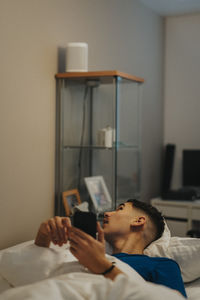 Teenage boy with smart phone lying on bed at home