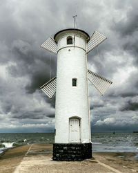 Lighthouse by sea against sky