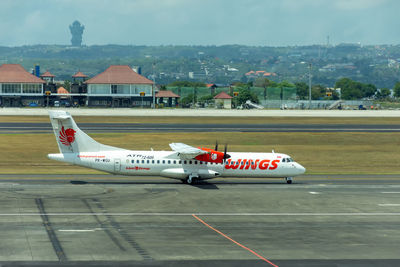 Airplane on airport runway against sky