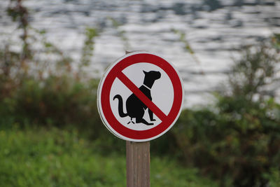 Close-up of warning sign against lake