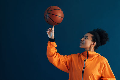 Man playing basketball against black background