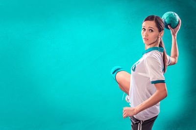 Sportswoman holding ball against blue background