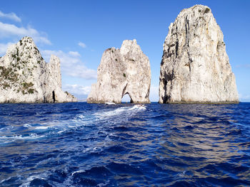 Rocks in sea against blue sky