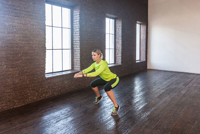 Full length of woman sitting on hardwood floor