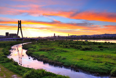 View of suspension bridge over river against cloudy sky