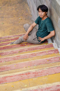 Portrait of young man sitting on footpath