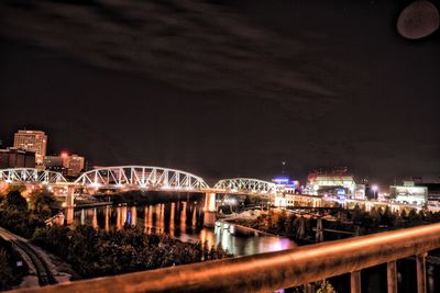 Illuminated bridge in city against sky at night