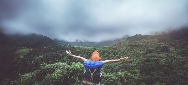 Rear view of woman standing on mountain against sky