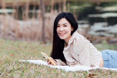 Portrait of young woman using laptop while sitting on field