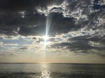 Sunlight streaming through clouds over sea