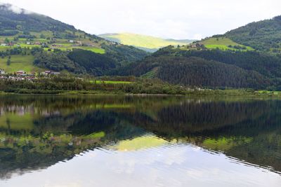 Scenic view of lake by mountains against sky